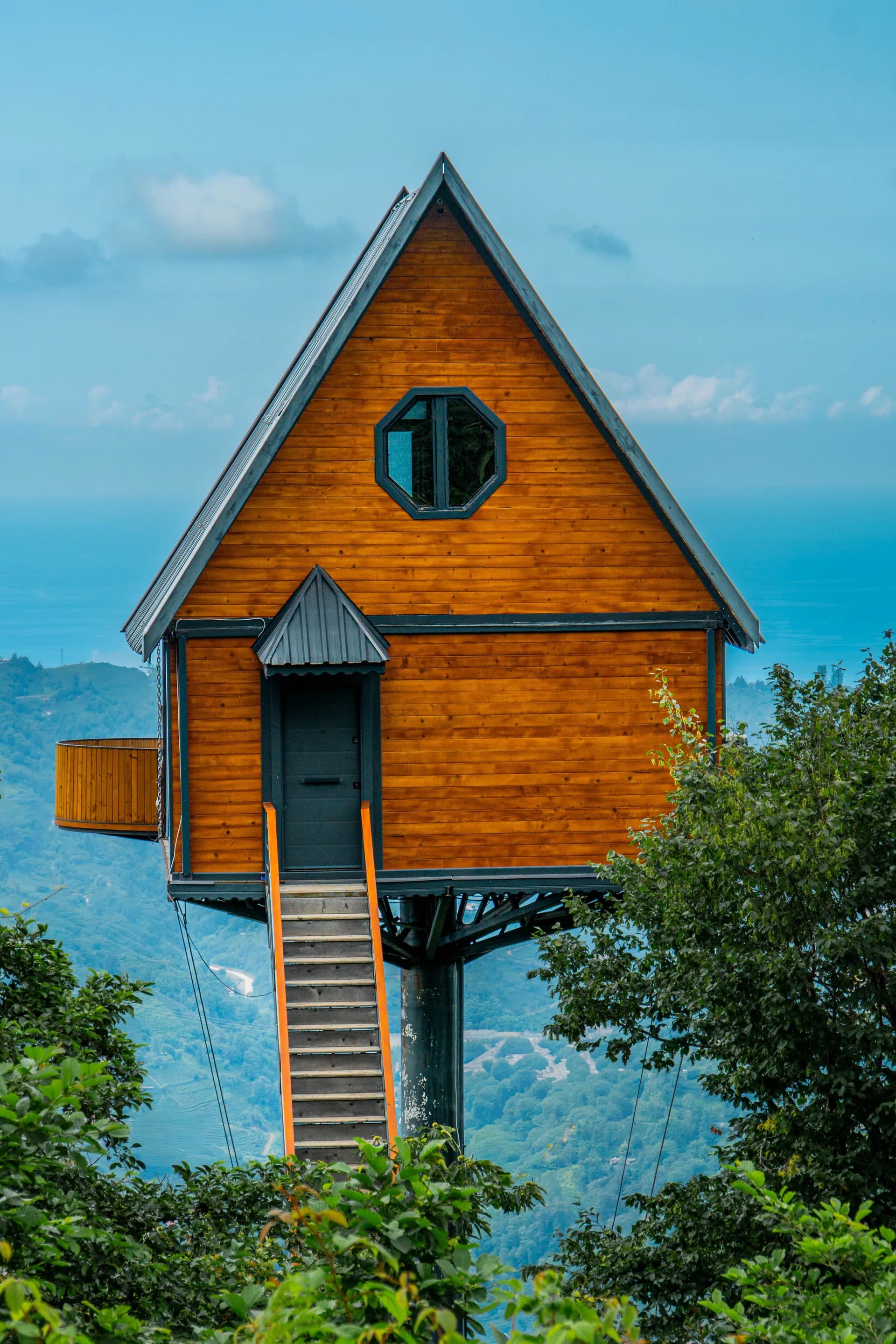 Imagen de ejemplo de BookNoFees: casa en un árbol de madera con escalera y vistas al valle
