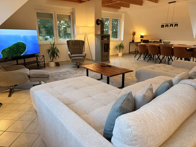 BookNoFees: alojamiento vacacional en Stuhr – Sala con sofá en forma de L, estufa de leña y área de comedor con mesa de madera
