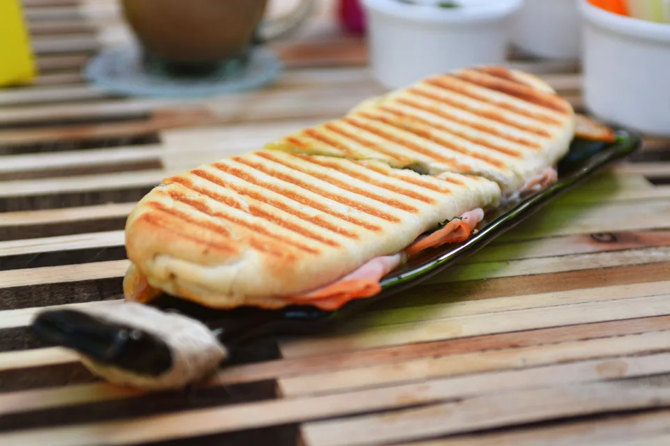 BookNoFees: Foto de ejemplo: Un panini tostado con marcas de la parrilla sobre un plato oscuro